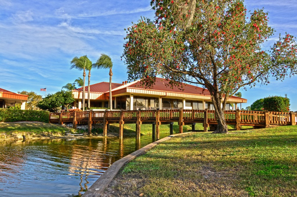 View of clubhouse overlooking golf course with tree and pond